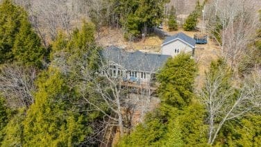 Above Fiew Of A Large Waterfront Cottage Surrounded By Tree's.